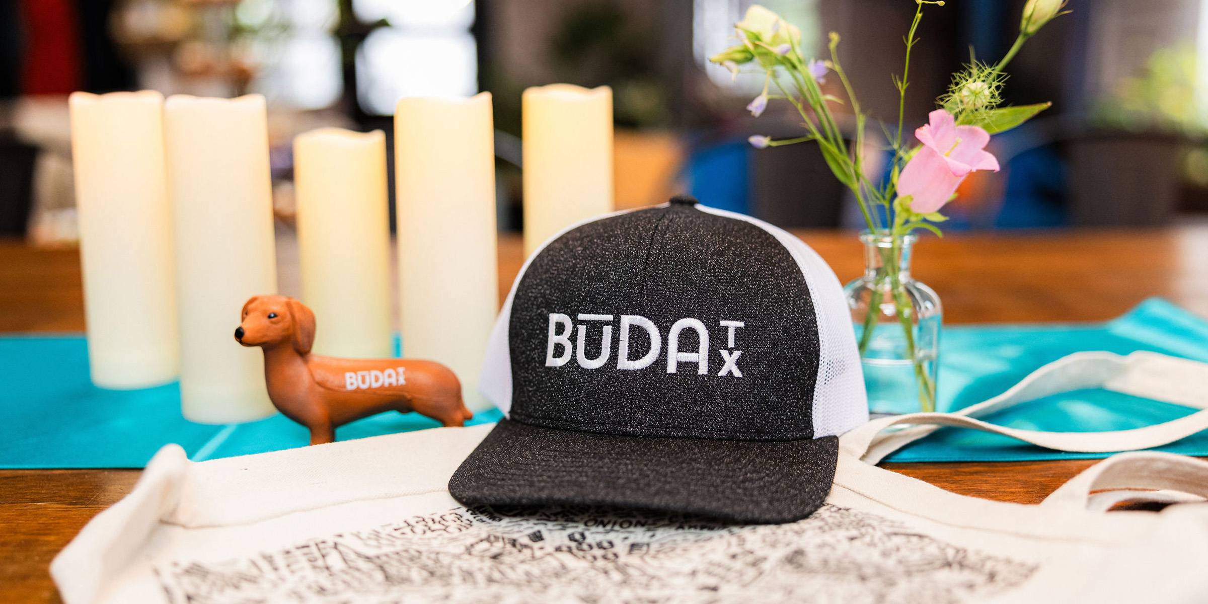 Buda EDC Cap and dog figurine on desk with candles in background